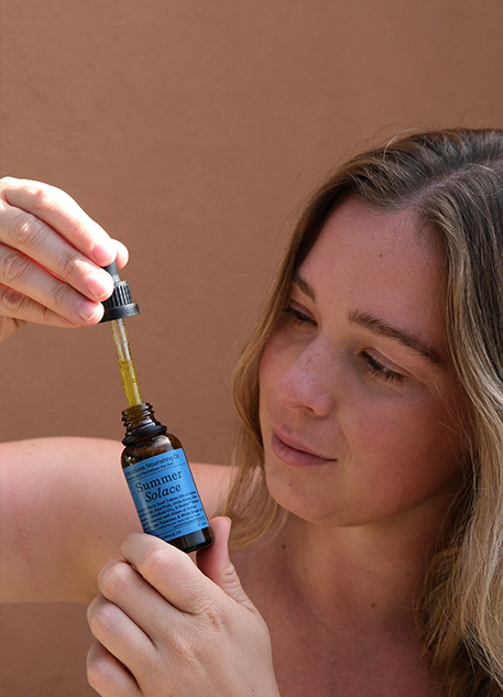 A woman holding a bottle of face oil against her skin