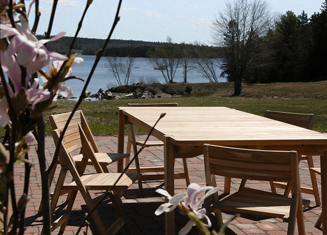 Wooden dining table outside on a patio with magnolia blossoms