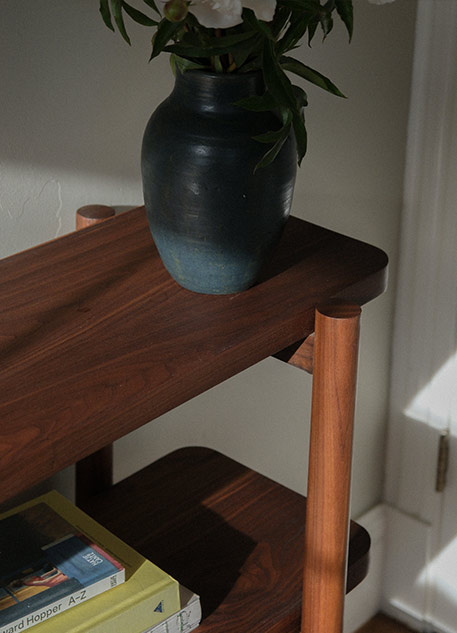 Wooden shelf holding books and a vase