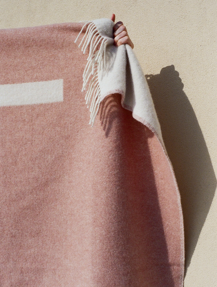 forestry-wool-river-wool-blanket-dusty-pink-product-image-holding-blanket-up-to-side