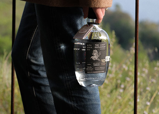 Cora carrying a bottle of The Lost Explorer Mezcal