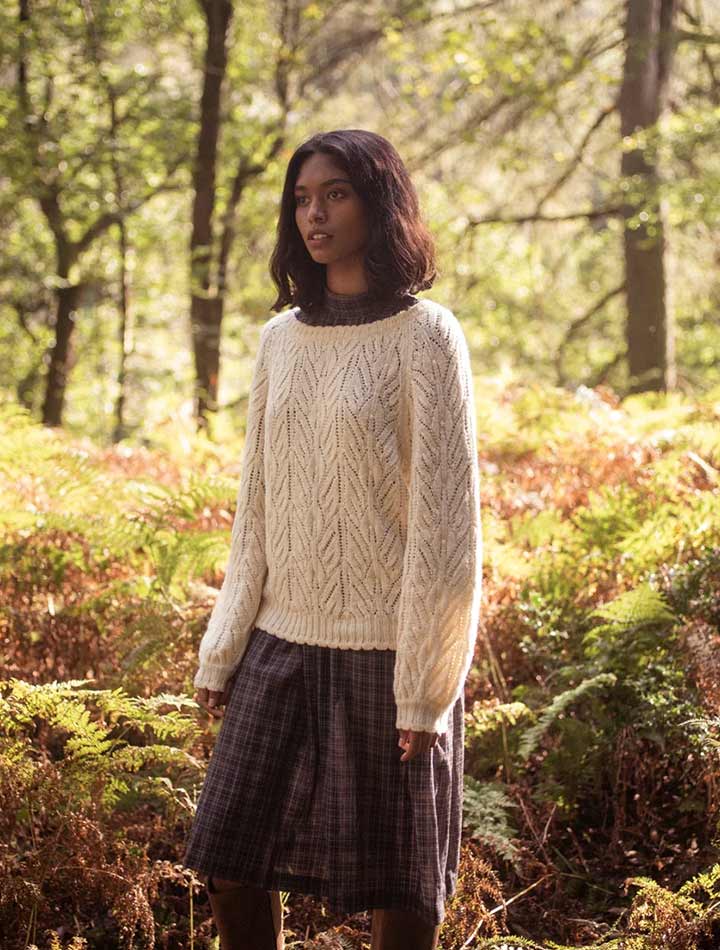 A woman in the forest wearing a white wool jumper
