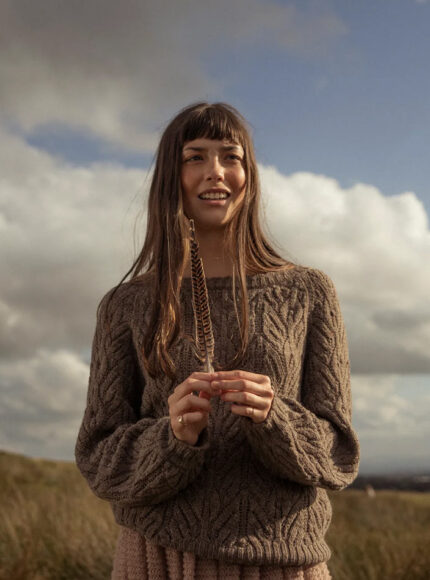 A woman wearing a brown wool jumper in front of a blue sky