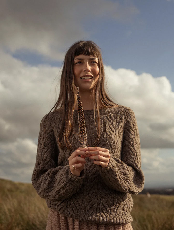 A woman wearing a brown wool jumper in front of a blue sky