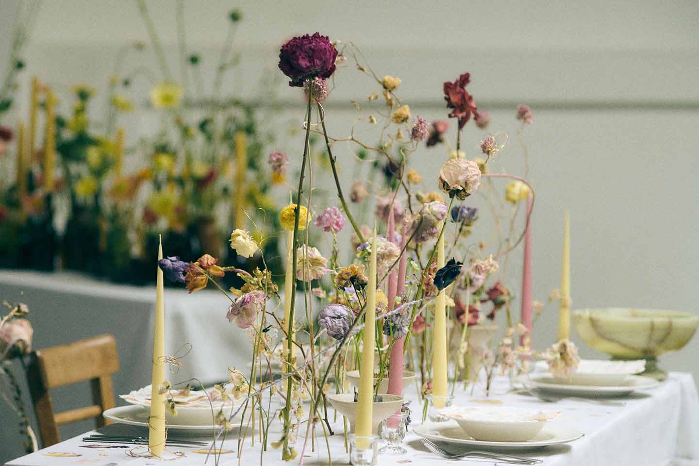 A table set with white linens and minimal British flowers