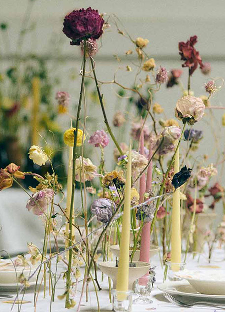 A table set with bud vases and different colored candles