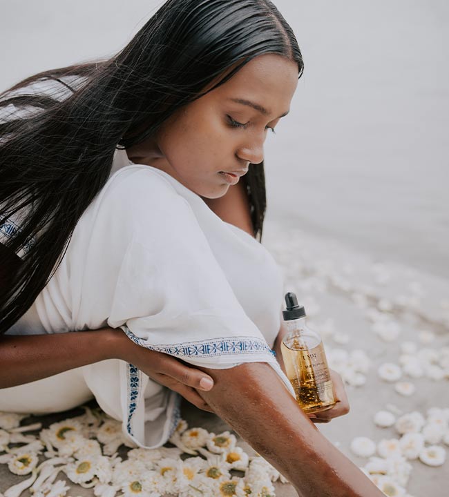 Lady applying oil to the skin during bathing ritual