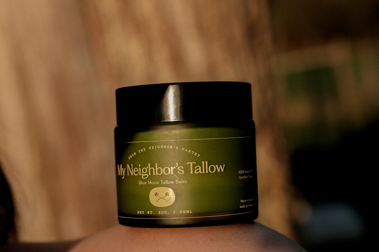 A jar of tallow balm on a woman's body