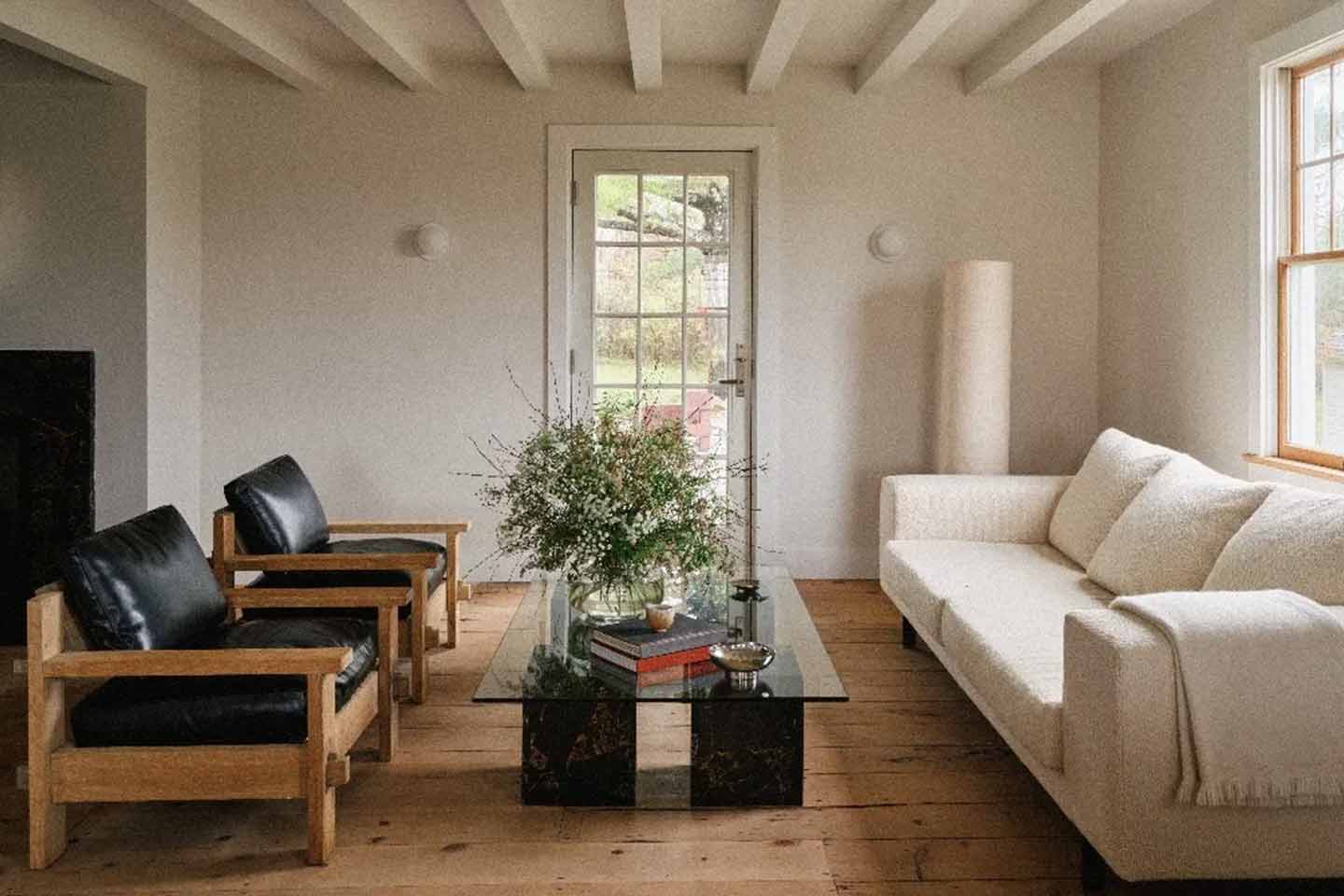 A living room with vintage furniture, wood floors and flowers.