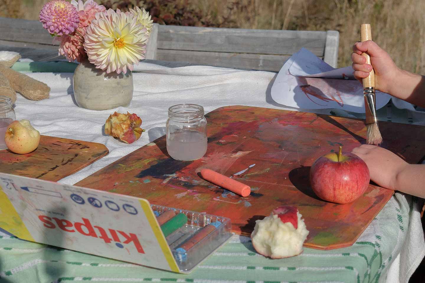 Children painting with watercolors on an outdoor table