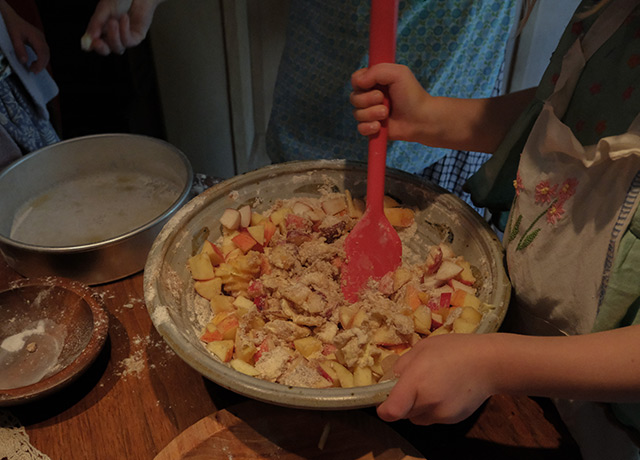 A child stirring apples into batter in a big bowl