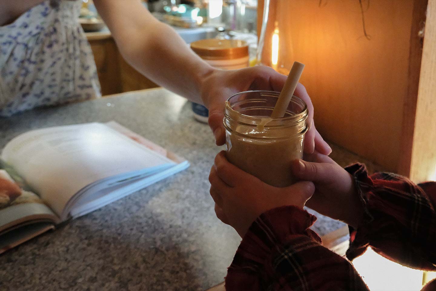 A mom hands her daughter a peanut butter smoothie