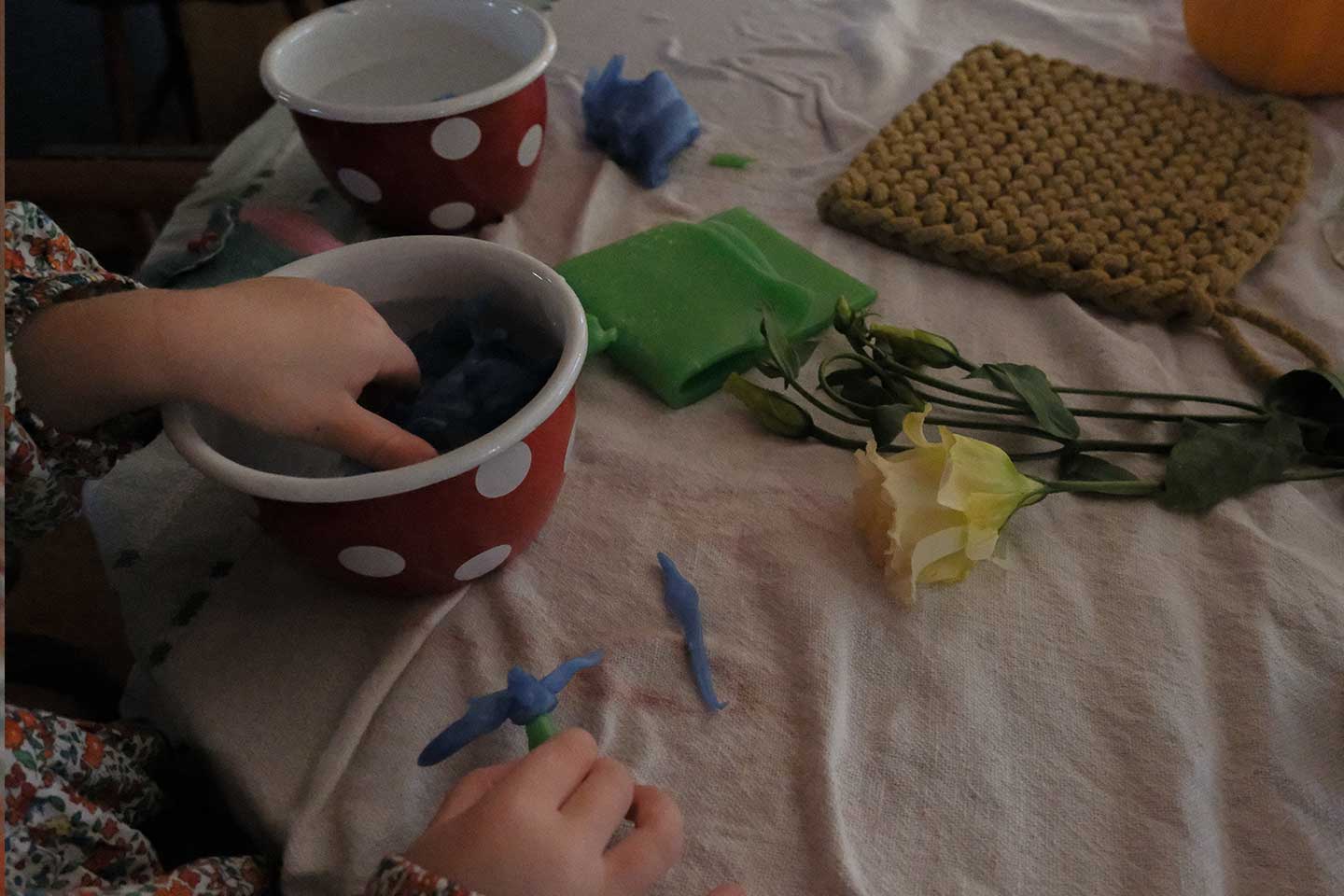A girl playing with beeswax on a kitchen table