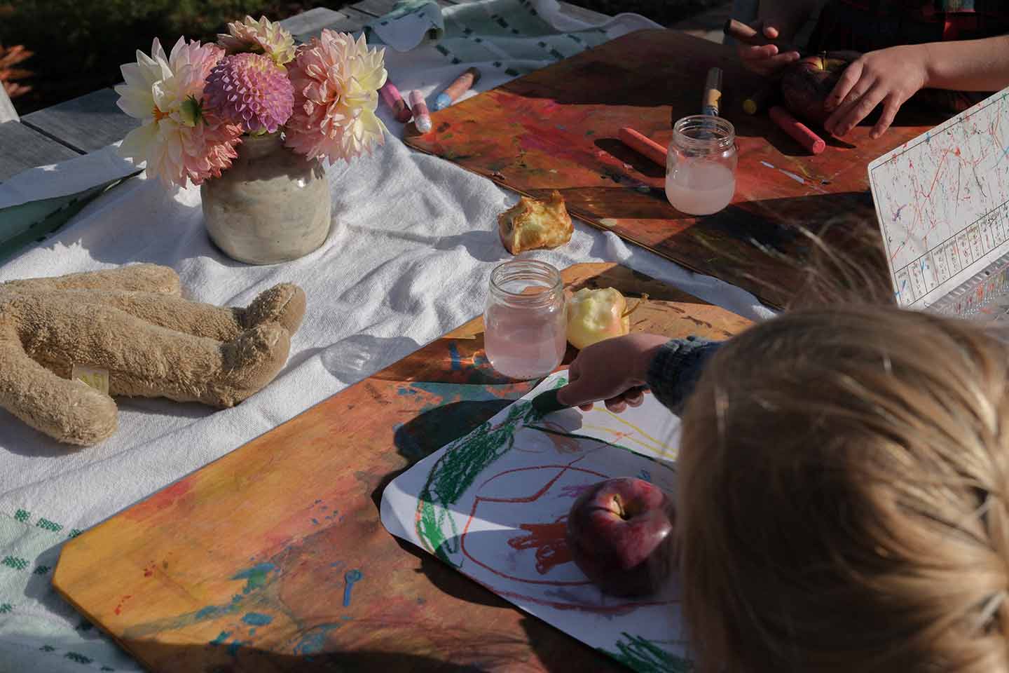 Children sat at a table with coloring supplies and apples