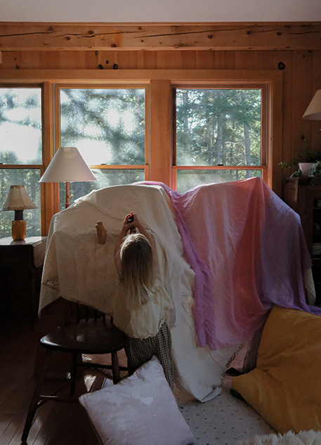 A young girl building a fort in a living room