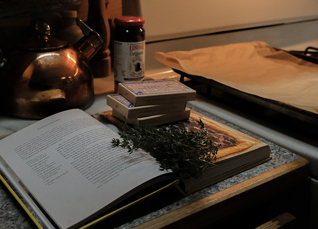 A cookbook open with cans of sardines on it and fresh thyme