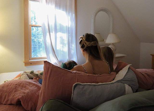 A woman in bed reading to her two young children