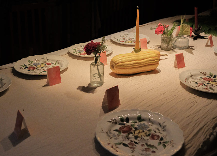 A dinner table set with flowered plates and squash