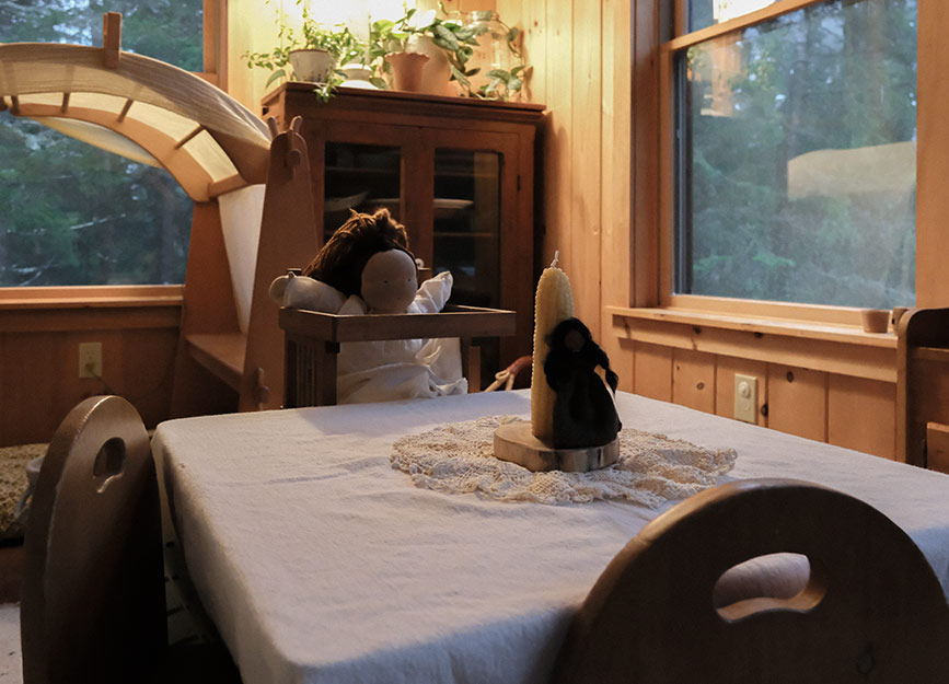 A child's table set up for dinner with dolls