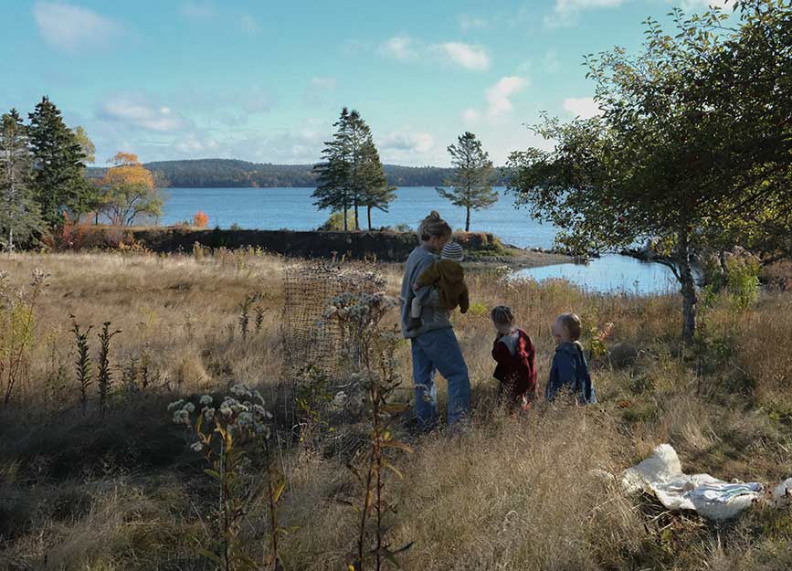 Mother in a meadow with her three children picking apples