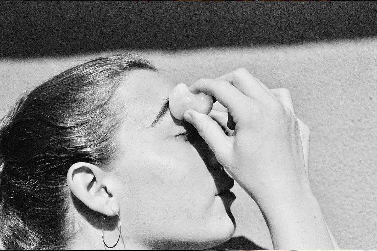 A woman using a gua sha on her eyes