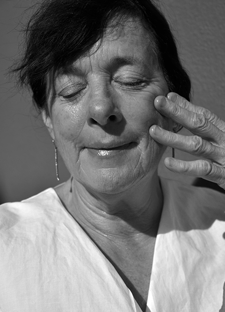 A black and white portrait of a woman giving herself a face massage