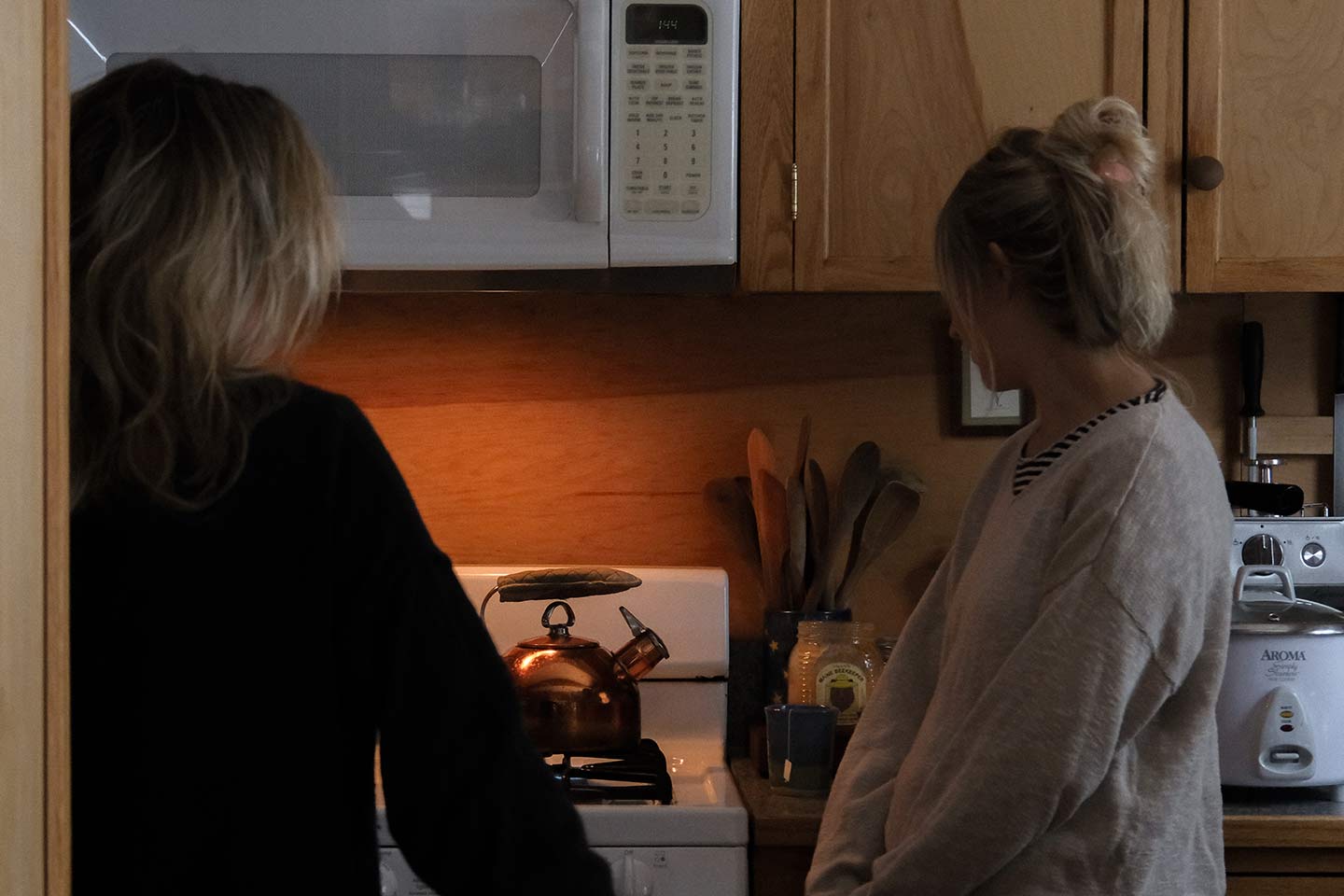 Two women in a kitchen watching a kettle boil