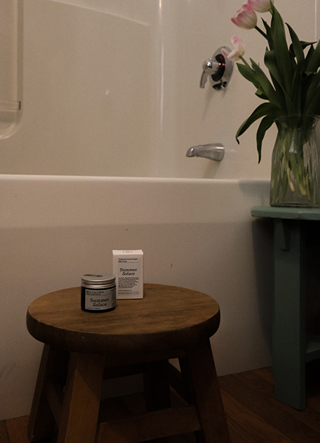 Summer Solace tallow on a stool in a bathroom with pink tulips