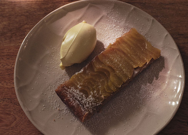 Apple tart presented on a white ceramic plate with ice cream
