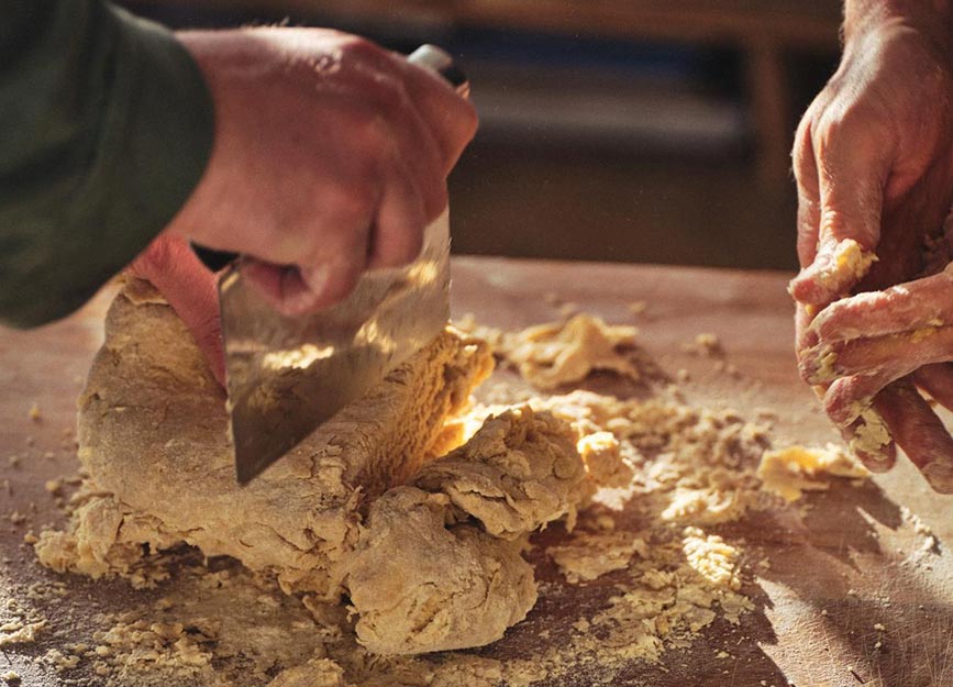 Two people making pasta dough in the sunlight