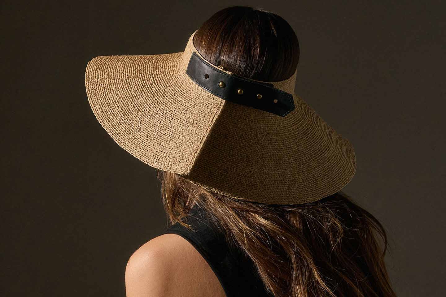 A brown haired woman wearing a woven hat