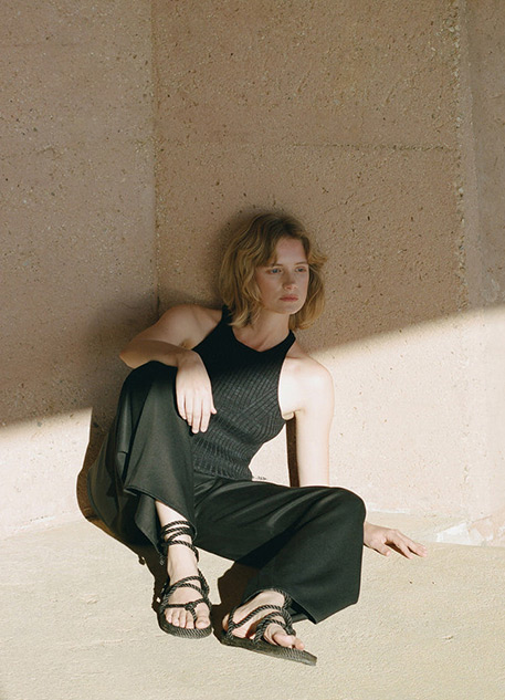 A blonde woman sitting on the ground in all black fashion