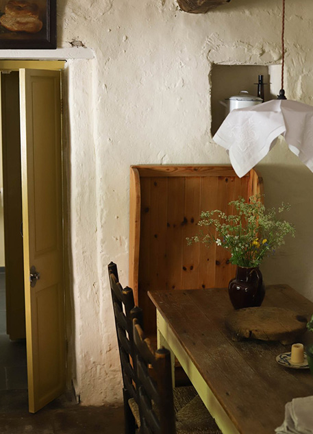 A farmhouse kitchen with a rustic wood table and vase of flowers