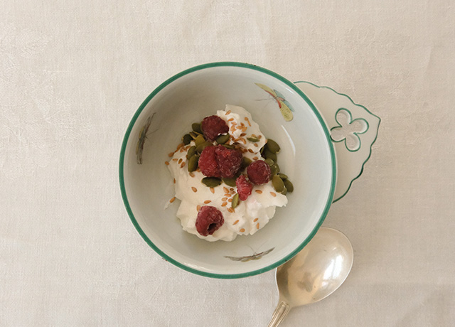 A bowl of granola with raspberries and yogurt