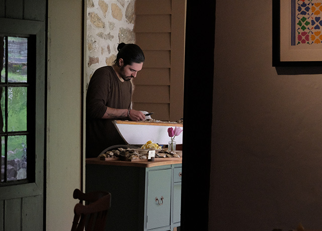 A man shucking oysters at a farm table