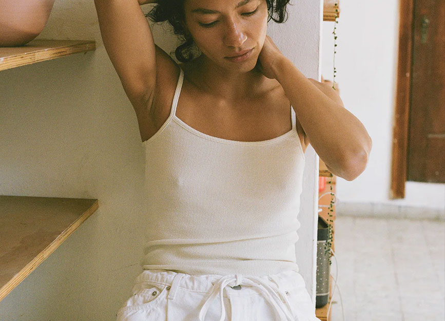 A woman sitting in a chair wearing a white cotton tank top