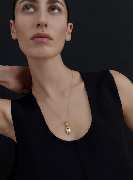 A woman in a black top wearing a pearl droplet necklace
