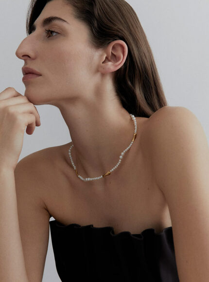 A woman wearing a gold and pearl choker around her neck