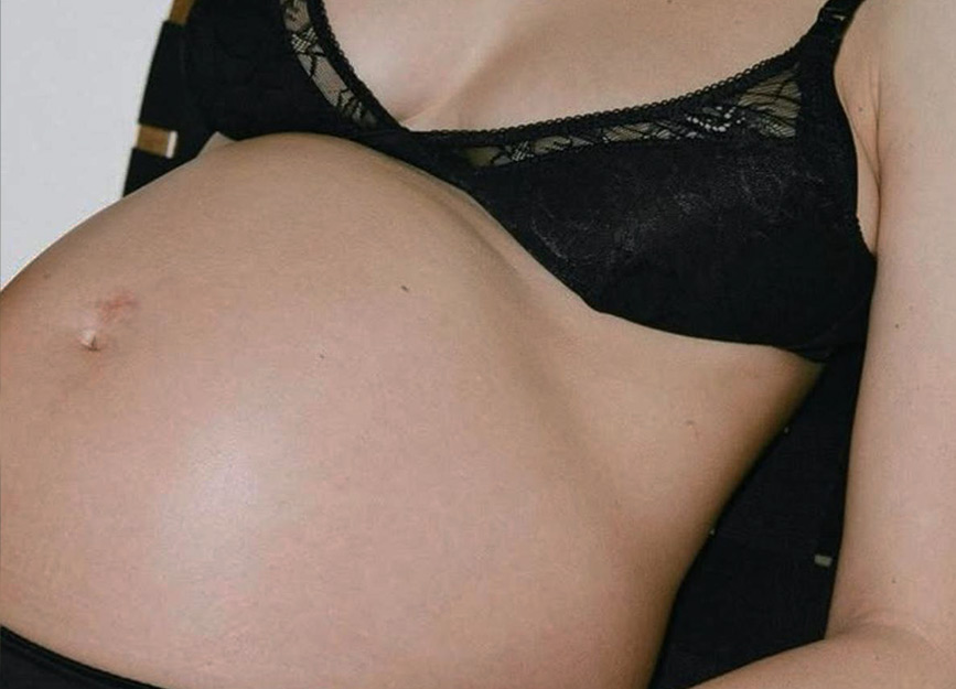 A pregnant woman in a black lace bra